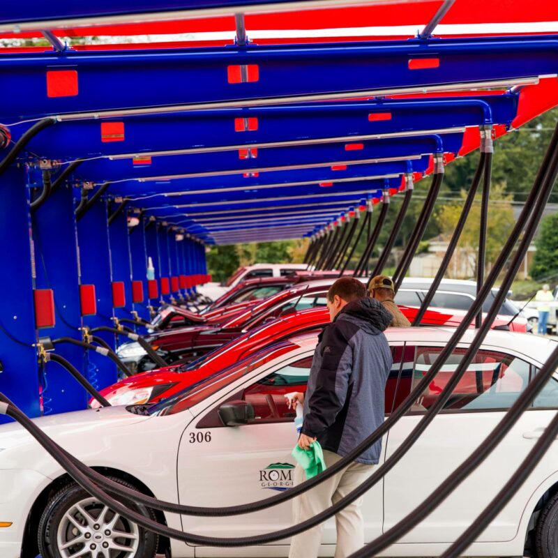 Multiple customer vehicles line up at Big Dan's self-service car wash and detailing area for cleaning
