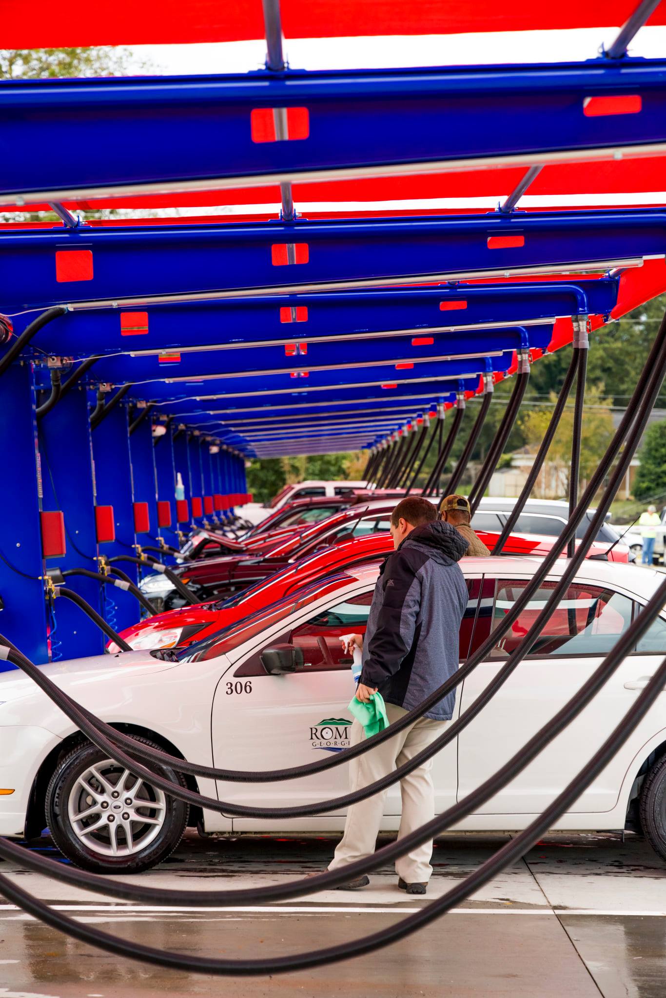 Multiple customer vehicles line up at Big Dan's self-service car wash and detailing area for cleaning